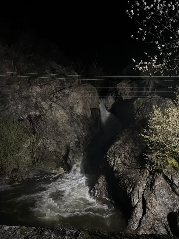 Woman photographs nighttime waterfall scene in Karlovo, Bulgaria