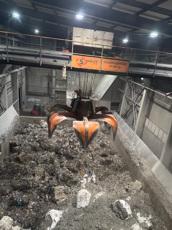 Excavator processes mixed waste pile at Bulgarian industrial site