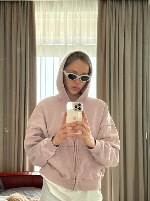 Person in pink hoodie takes indoor selfies with poodle