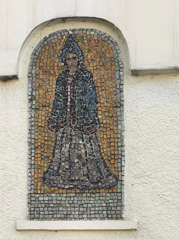 Ornate mosaic facade with robed figures and landscape murals