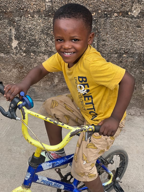 Young boy photographed smiling with bicycle in Jos, Nigeria