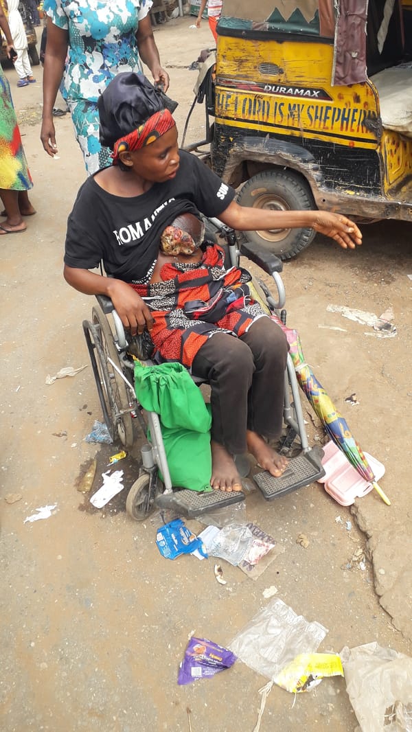 Street scene observed in Nkpor, Nigeria with wheelchair-bound woman