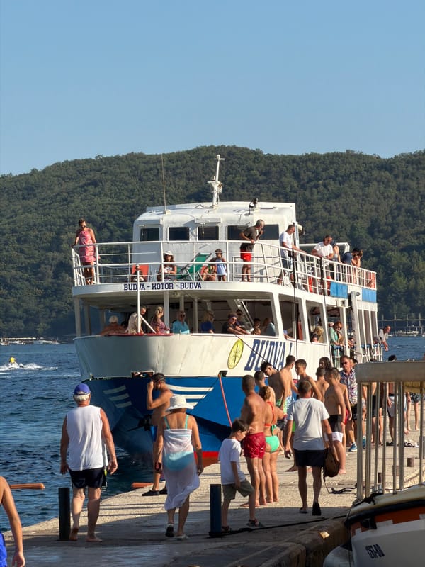 Budva's waterfront buzzing — ferries, boats, and a packed beach
