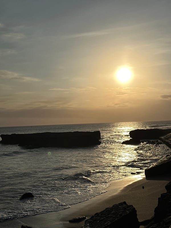 People gather on rocky outcrop during hazy morning in North Kuta