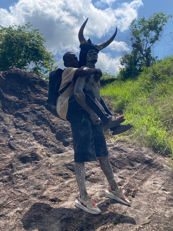 Gray-painted man gives boy piggyback ride in Afikpo