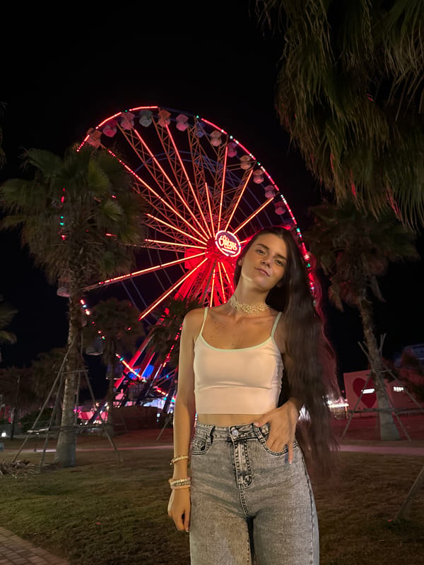Woman photographs at Vietnam amusement park with Ferris wheel