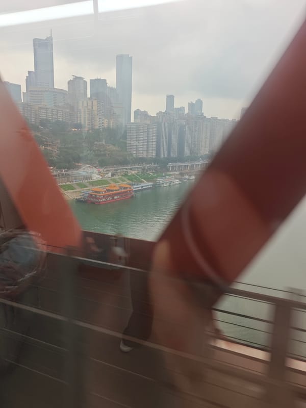 Passenger photographs Chongqing cityscape from moving bridge crossing