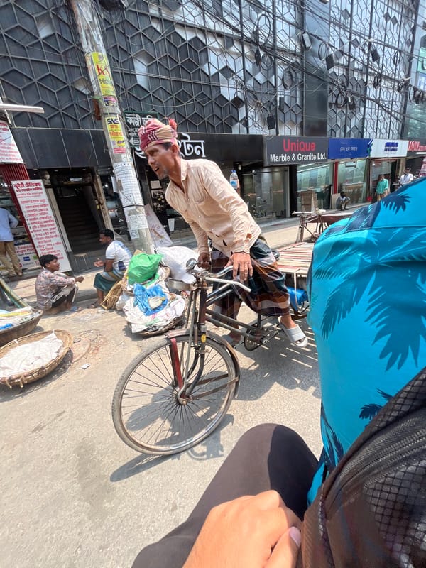 Elderly cyclist transports textiles through Dhaka streets
