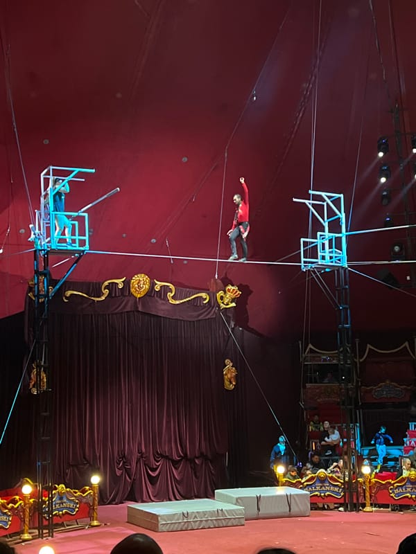 Circus acrobat performs tightrope act between elevated platforms