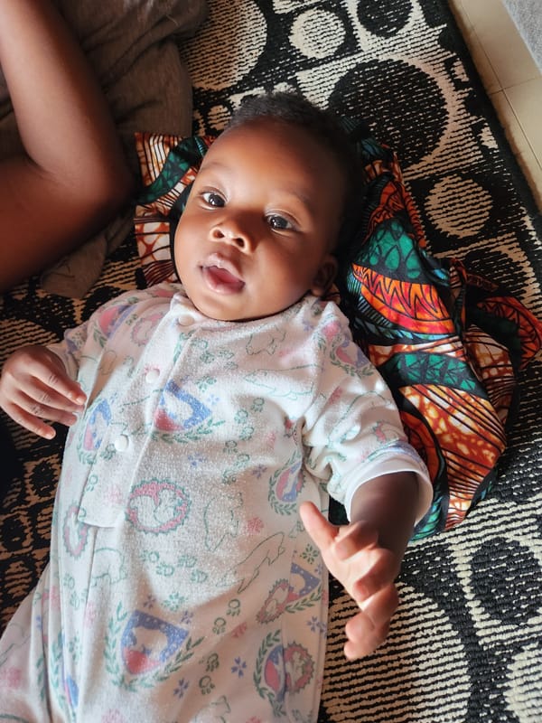 Baby on a rug and street life in Sabon Tasha, Nigeria