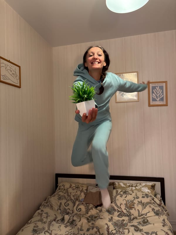 Woman jumps joyfully indoors holding plant in Gelendzhik