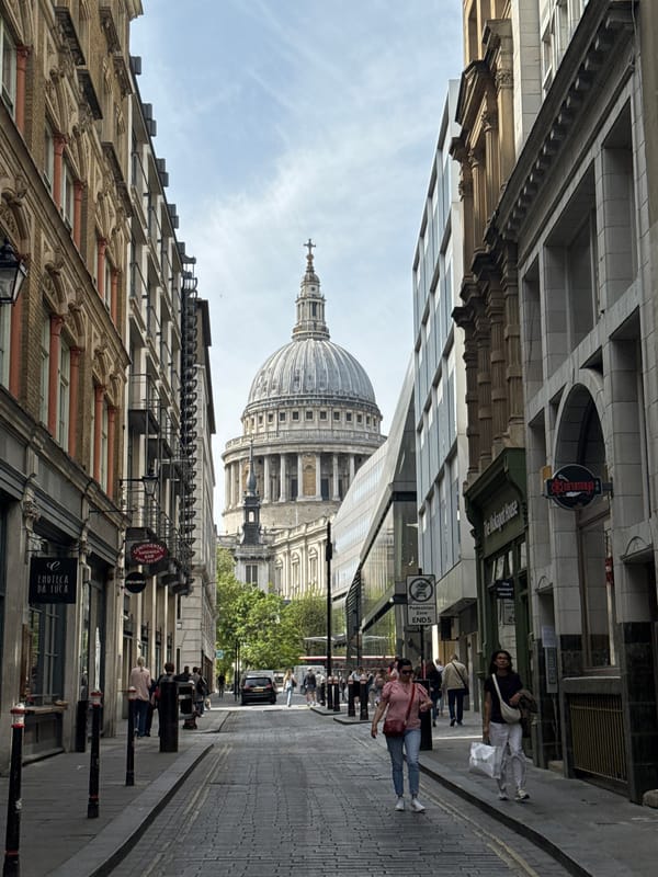 Pedestrians stroll London cobblestone street with St. Paul's Cathedral backdrop