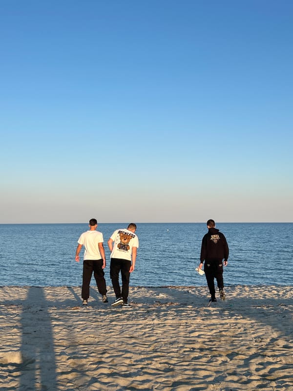 Three men gather on Greek beach under clear skies