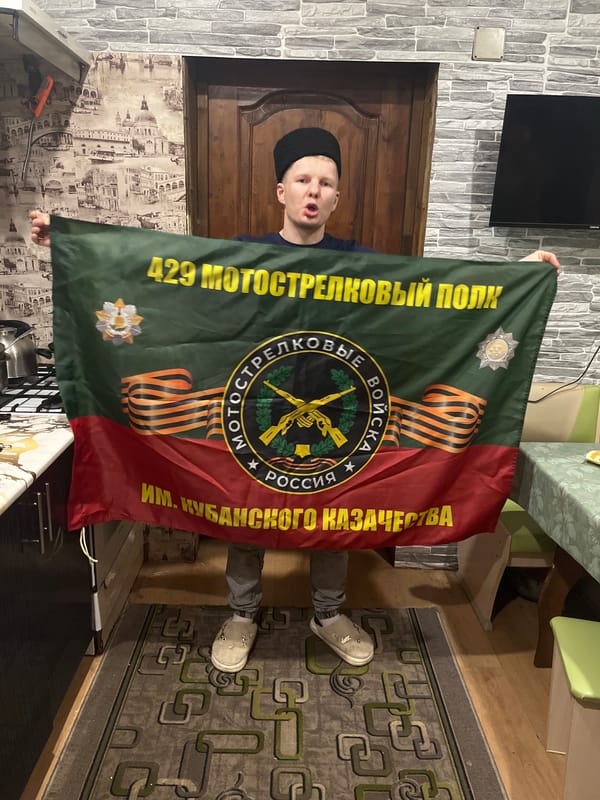 Men display 429th Motorized Rifle Regiment flag in Vesyoloye