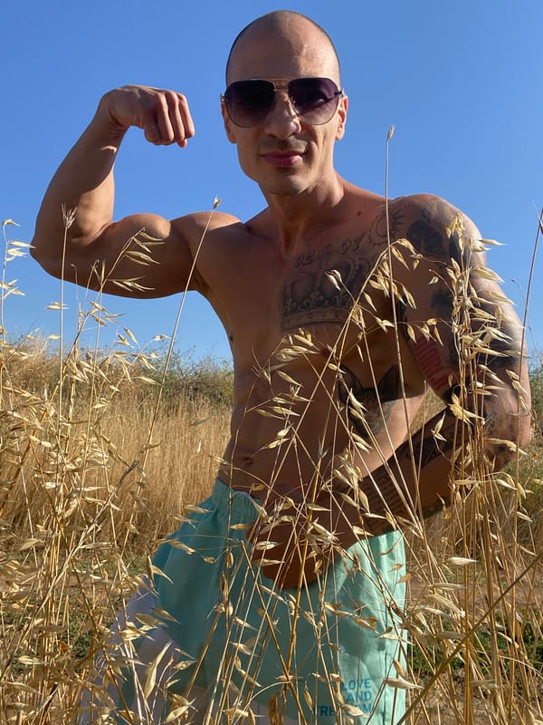 Tattooed figure poses and jumps in a dry Bulgarian field