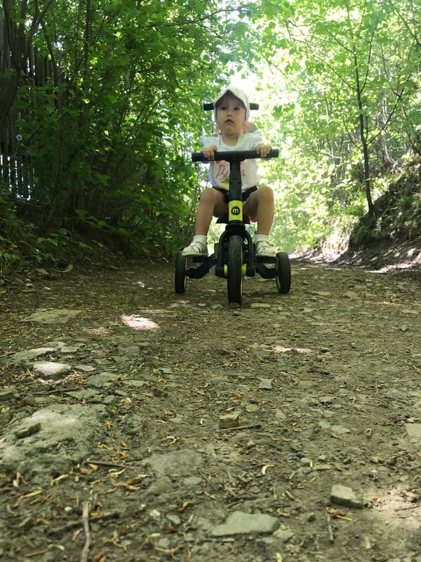Child rides tricycle during family outing in Wisła, Poland