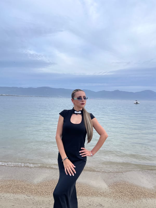 Woman poses on cloudy Kuşadası beach amid typical seaside setup