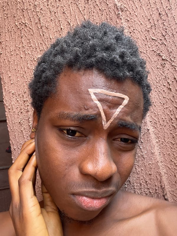 Person paints white triangle on forehead in Nkpor Nigeria