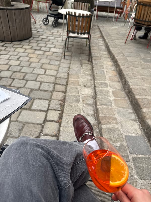 Person enjoys orange cocktail at Vienna restaurant table