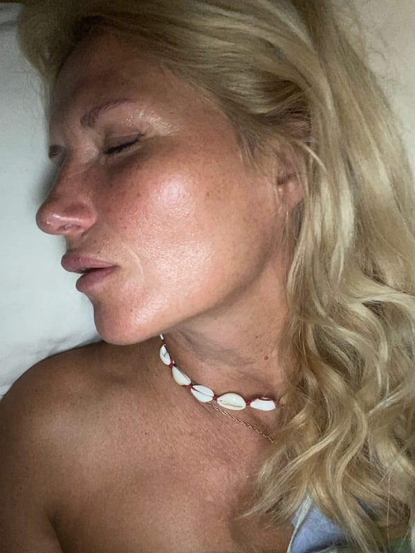 Shell necklace and closed eyes on a white surface, Santorini