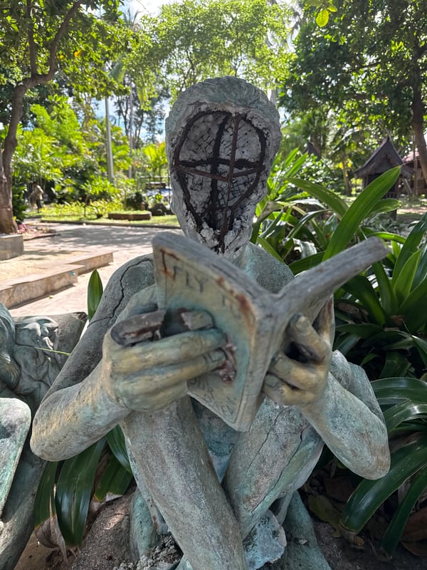 Beach life and a crumbling bronze reader at Chaweng