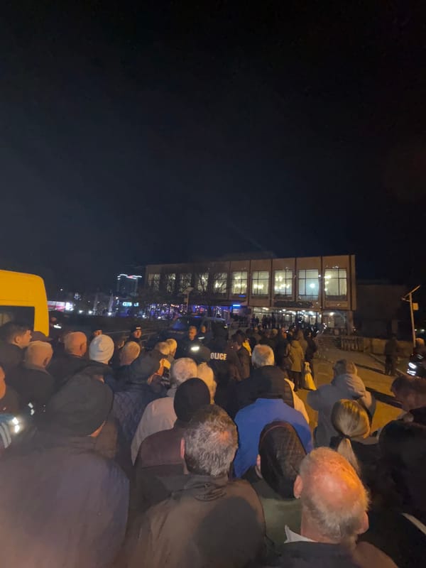 Nighttime crowd gathers outside building in Kardzhali, police present