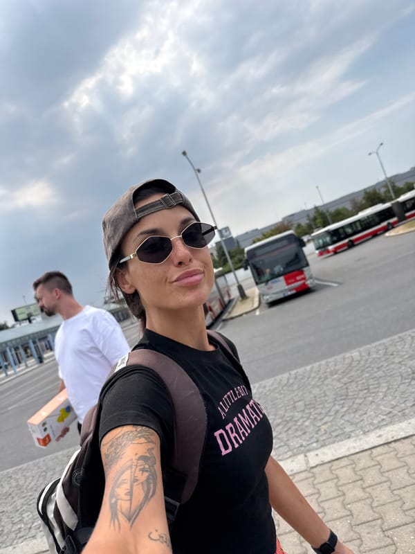 Selfie against a cloudy Prague sky, backpack and tattoo in view