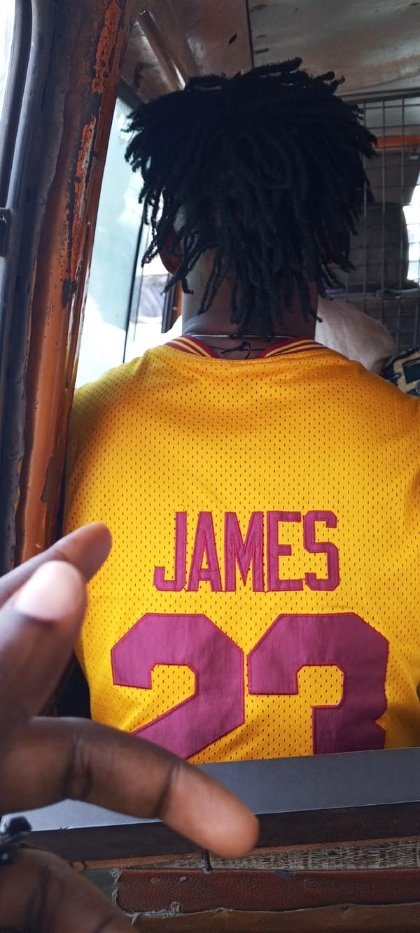 Street-level Lagos: traffic, UBA House, and a jersey-clad passenger