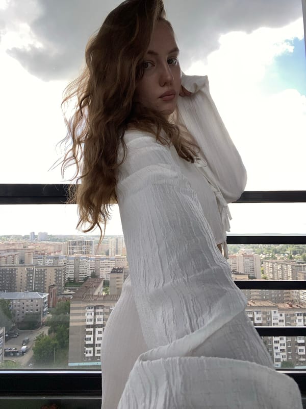 Woman photographed by window overlooking Izhevsk cityscape