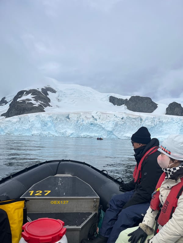 Tourist group observes glacier from inflatable boat amid cloudy weather
