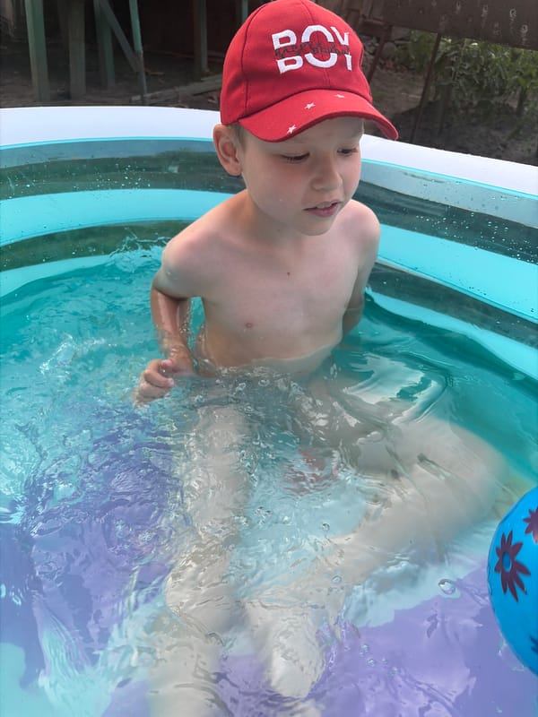 Kids cooling off in a backyard inflatable pool on a sunny afternoon