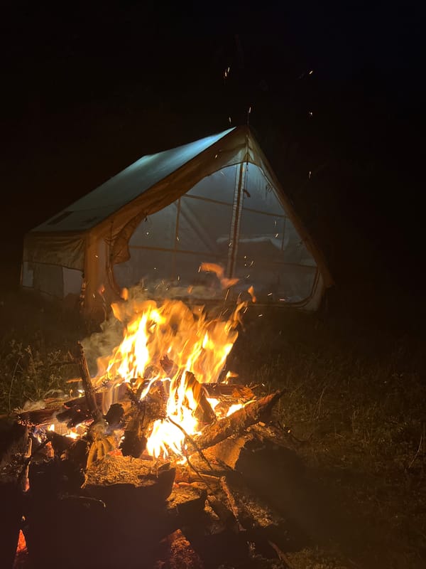 Campfire and tent under a full moon in rural Bulgaria