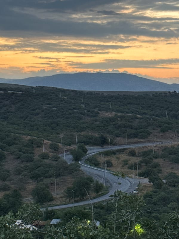 Manas at dusk: hillside roads, flags, and city lights at night
