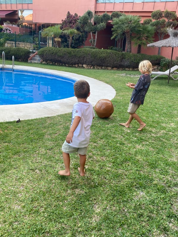 Kids playing with an inflatable ball by a backyard pool in Spain
