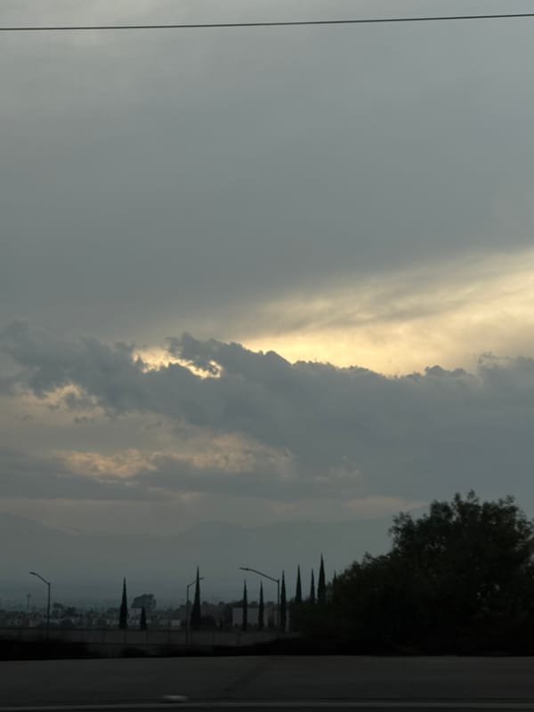 Evening sky observation shows yellow light through grey clouds