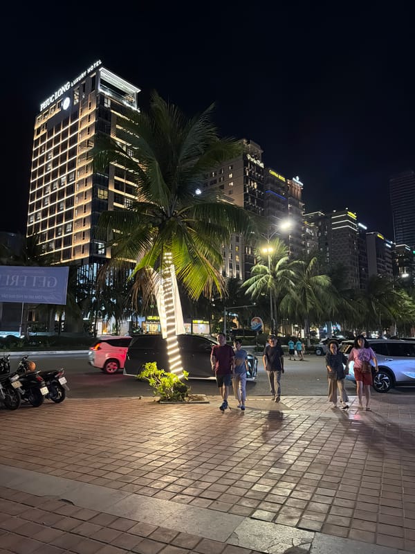 Nighttime walkway scene in Da Nang with kiosk and hotels