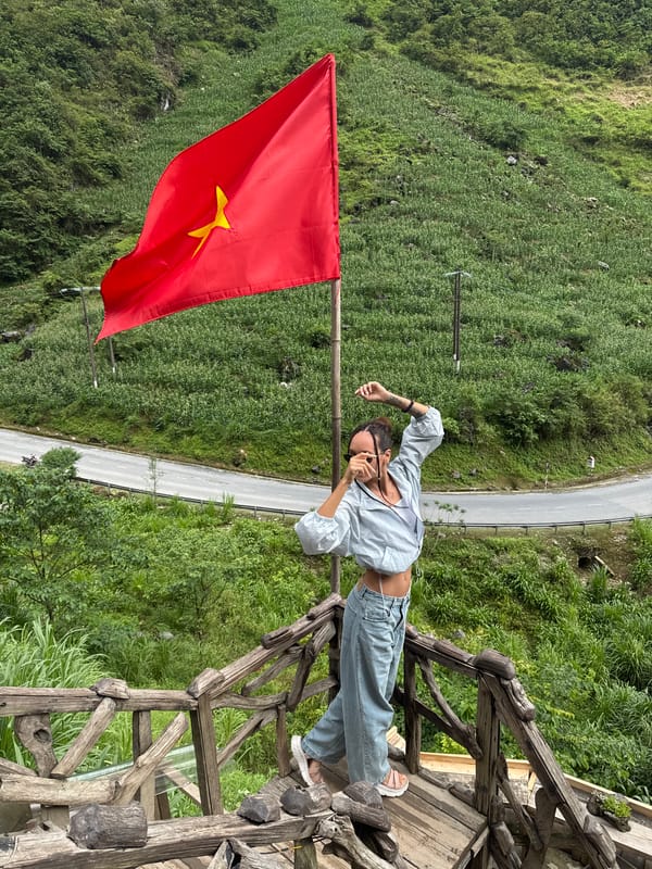 Woman poses near Vietnamese flag in Yên Minh Commune