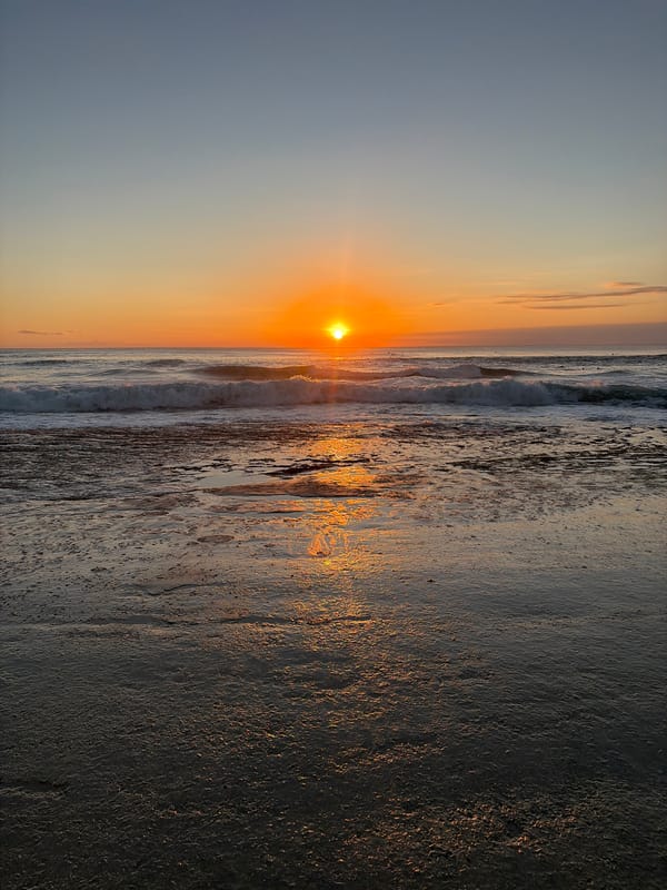 Golden sunset over the beach, sand, and breaking waves