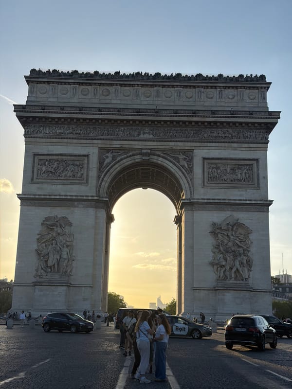 Tourist photographs capture Arc de Triomphe during sunny evening