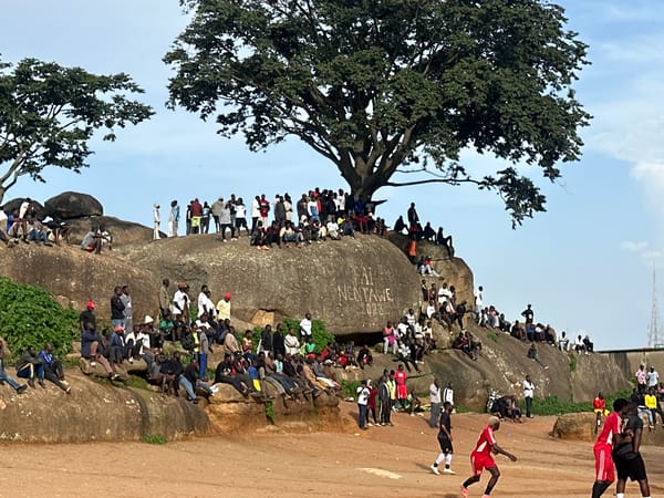 Pickup football match in Jos, Nigeria, watched from rocky hillside