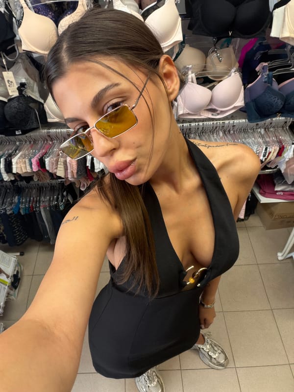 Selfie pair in a Karnobat lingerie store, same outfit, seconds apart.