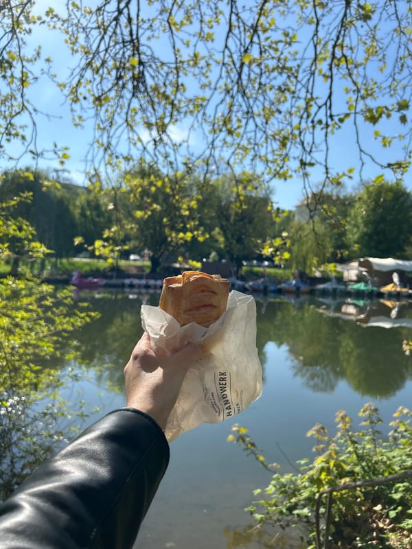 Person with black jacket holds pastry outdoors
