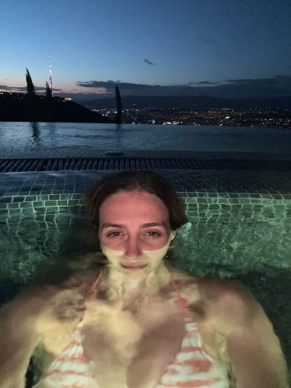 Rooftop pool evening with Tbilisi skyline at dusk