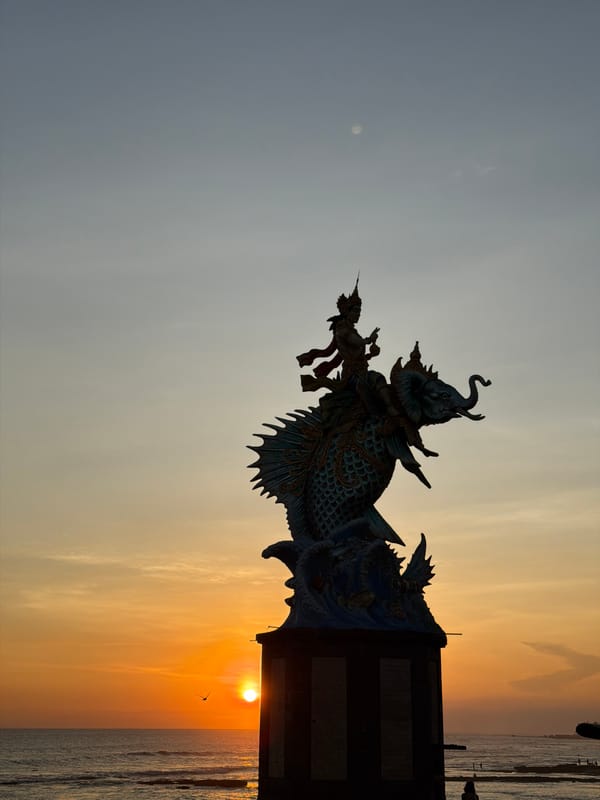 Coastal statue and beach activity observed in Mengwi, Indonesia