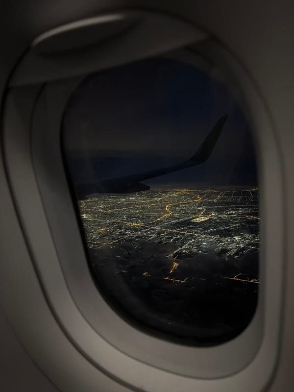 Passenger films nighttime aerial views of illuminated Bangkok from aircraft