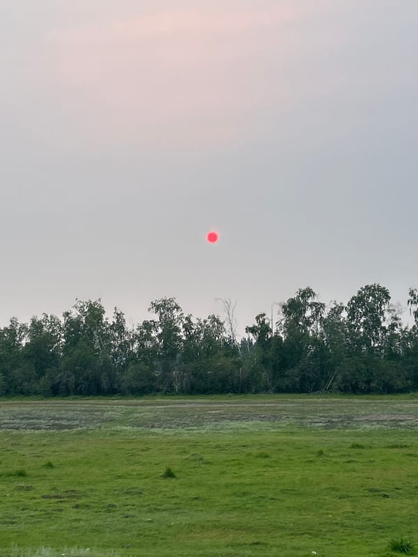 Red sun glows through heavy smoke haze over rural Siberia
