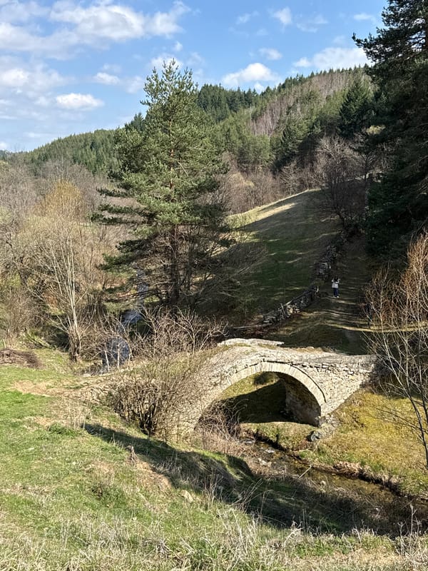 Person crosses historic stone bridge in rural Zagrajden, Bulgaria