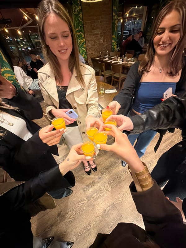 Five women toast with shots at Milan table