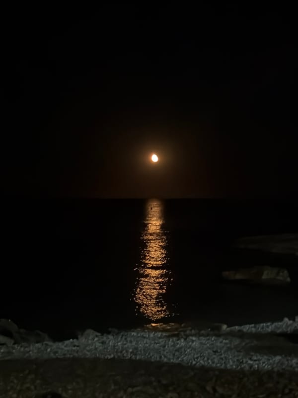 Summer night on the Xàbia waterfront — moon, crowds, and neon
