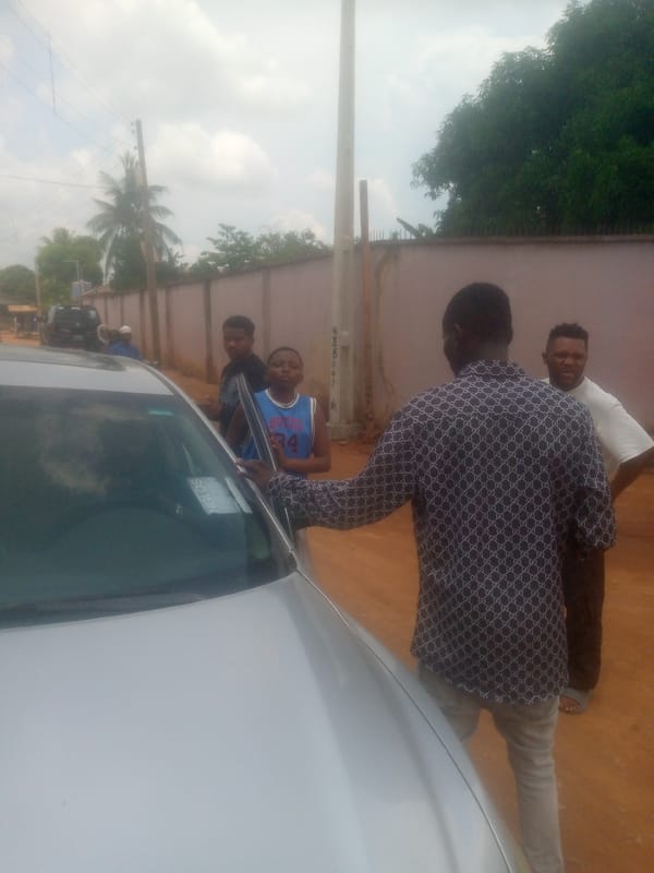Film crew gathers around silver car in residential area